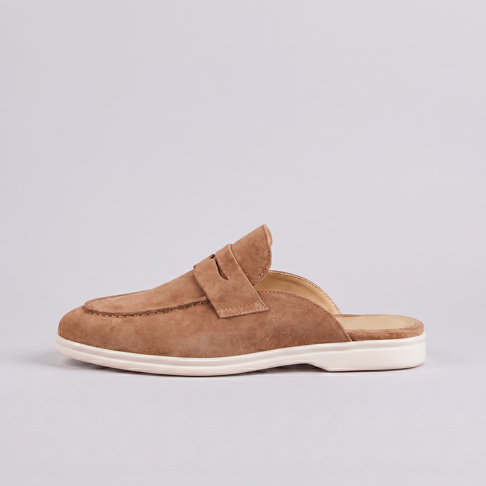 Brown slip-on shoe with a white sole on a light gray background
