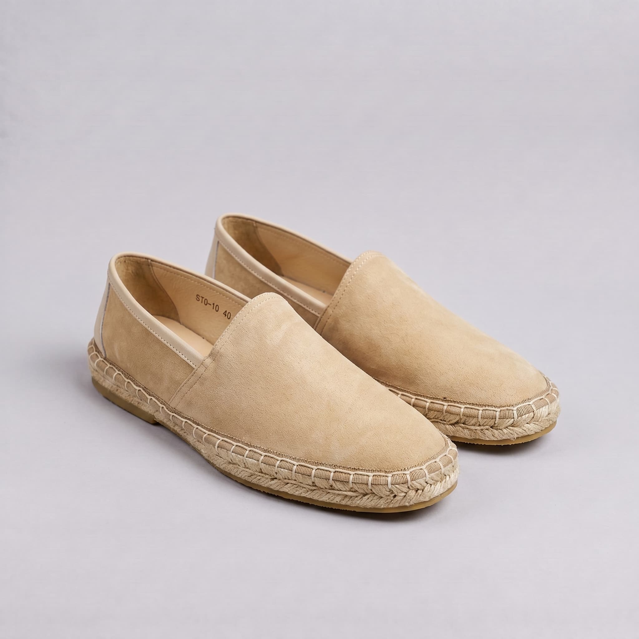 Pair of beige espadrilles on a light gray background