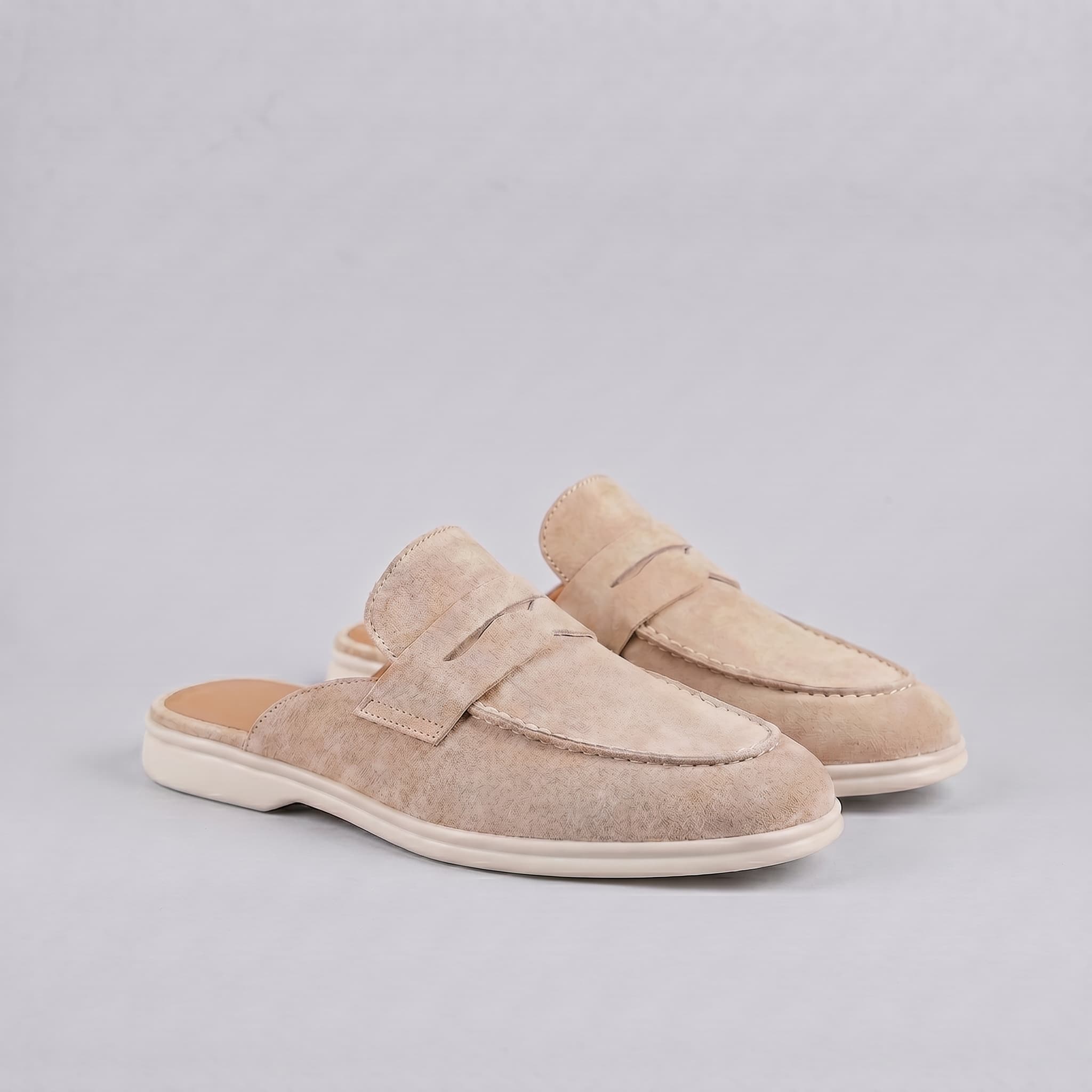 Pair of beige loafers on a light gray background