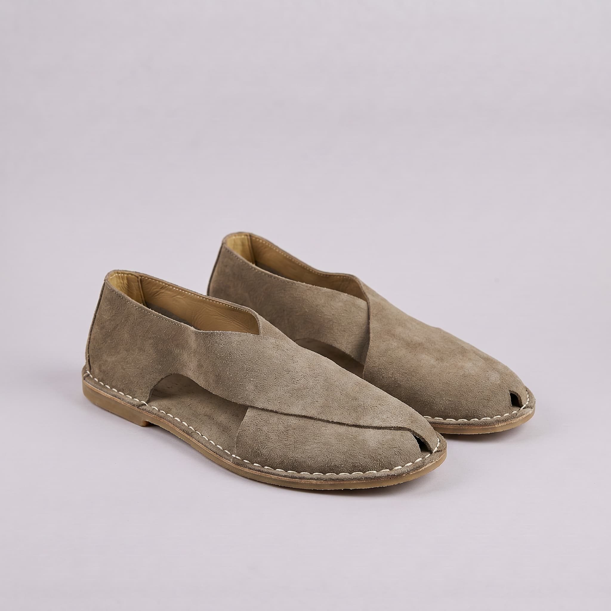 Pair of beige suede open-toe shoes on a light gray background