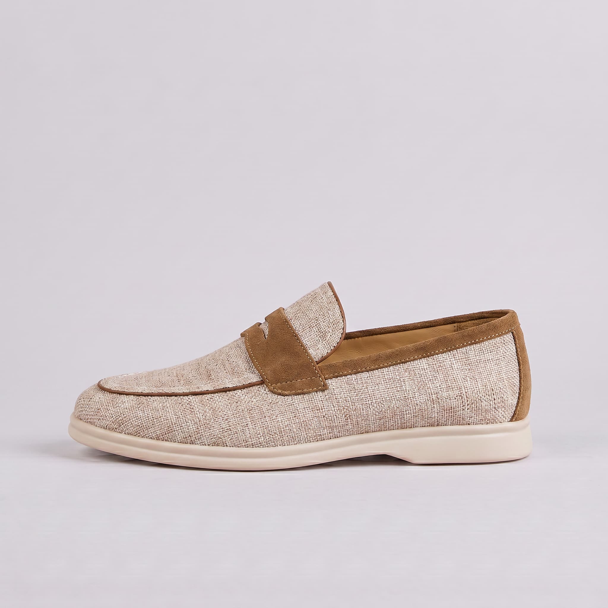 Beige loafer shoe with brown accents on a light gray background