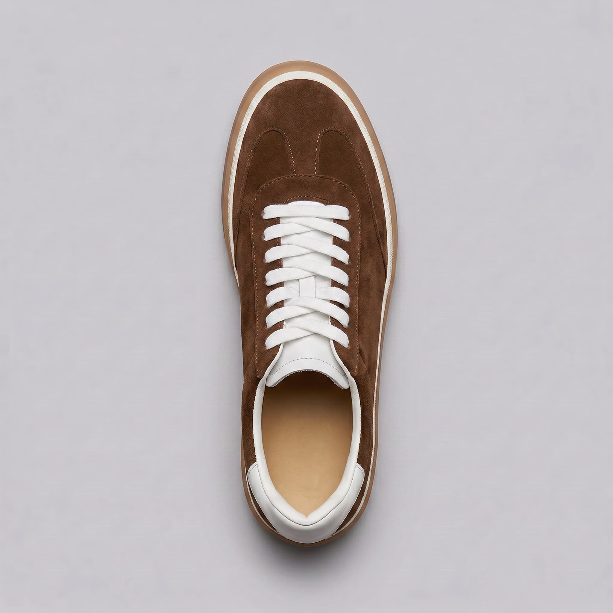 Brown suede sneaker with white laces on a gray background