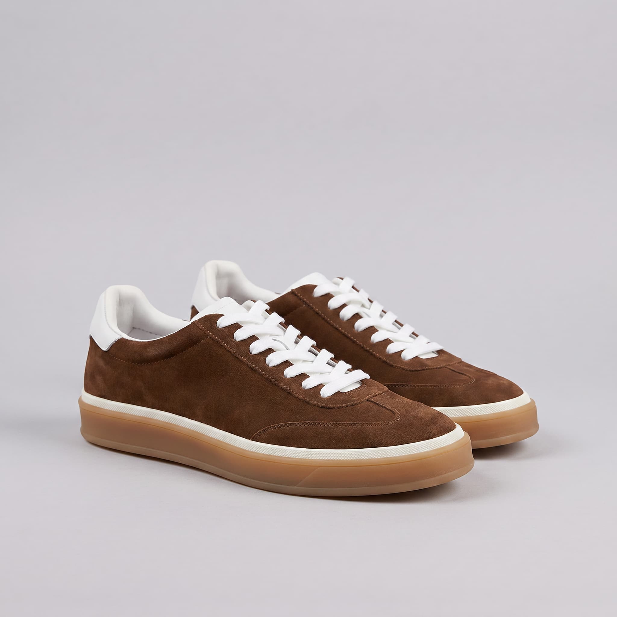 Brown sneakers with white laces and soles on a gray background