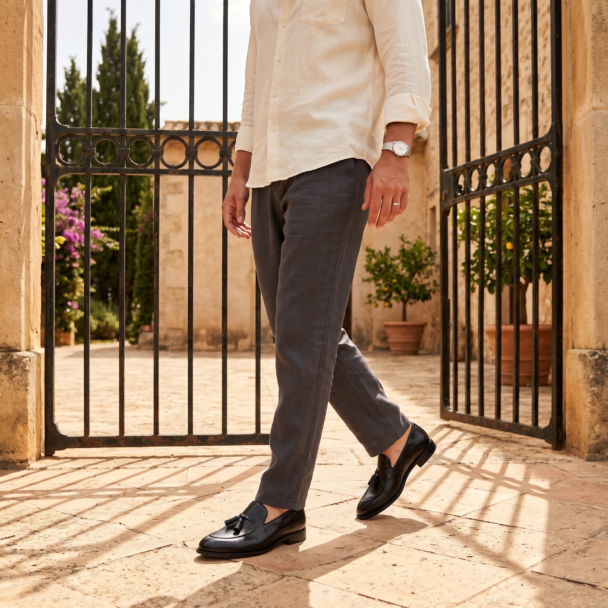 Person walking through a gate wearing a light-colored shirt, dark pants, and black shoes.