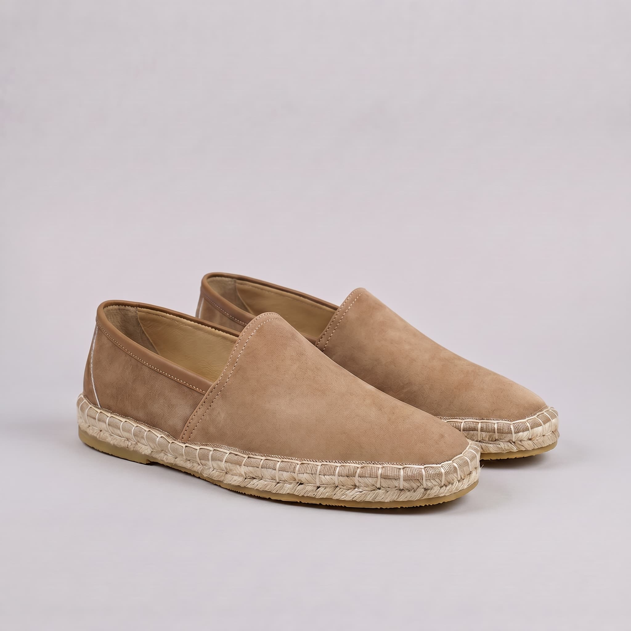Pair of tan espadrilles on a light gray background