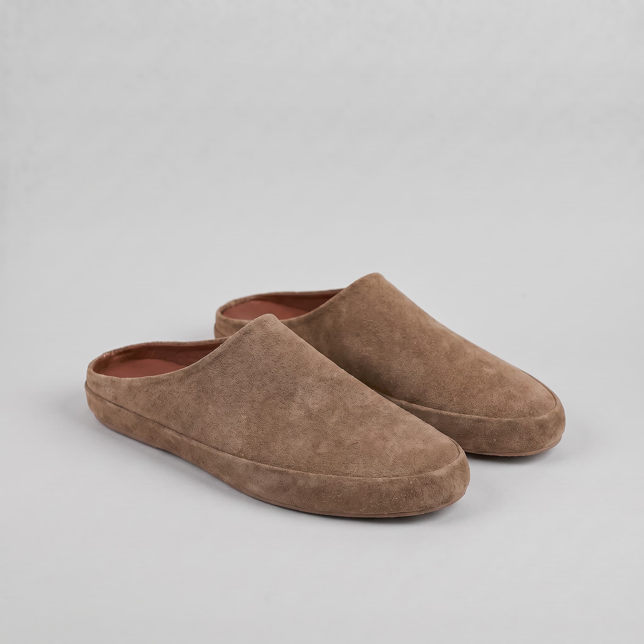 Pair of brown suede slippers on a light gray background
