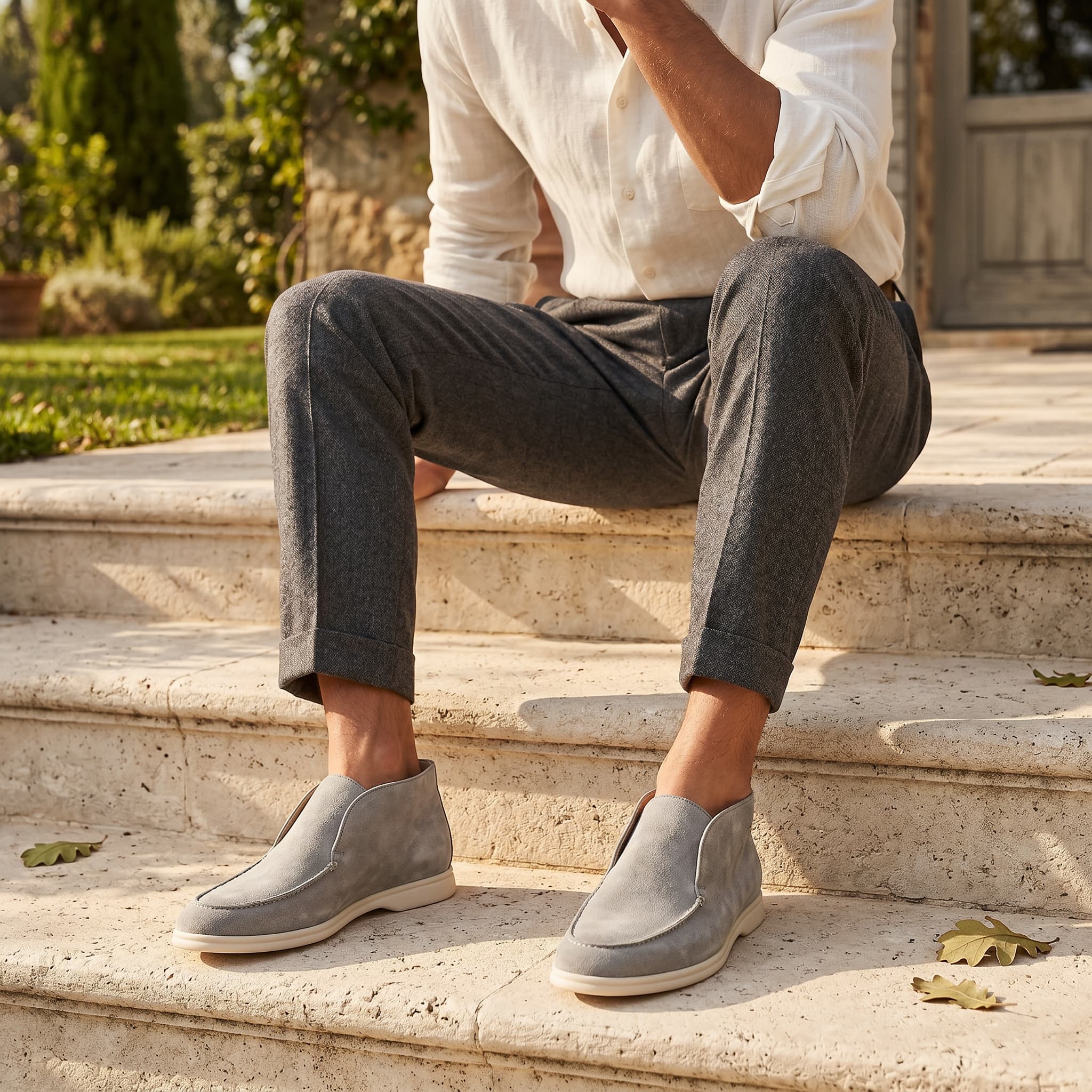 Person sitting on steps wearing gray suede shoes and gray pants.