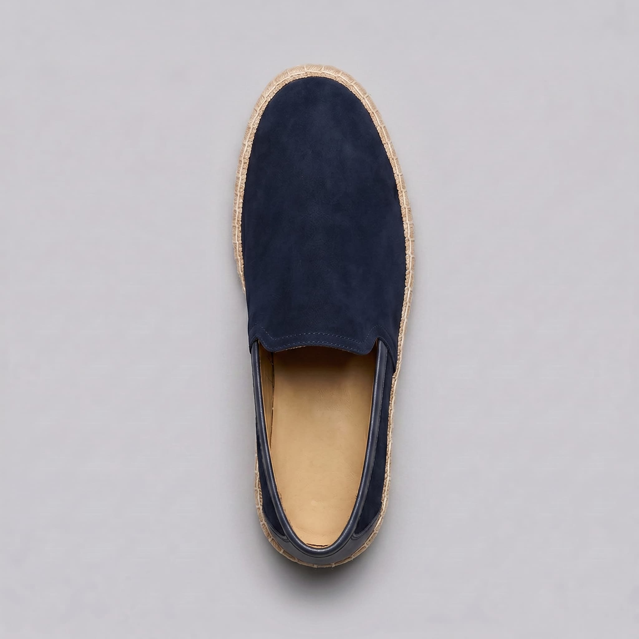 Navy slip-on shoe with jute sole on a gray background