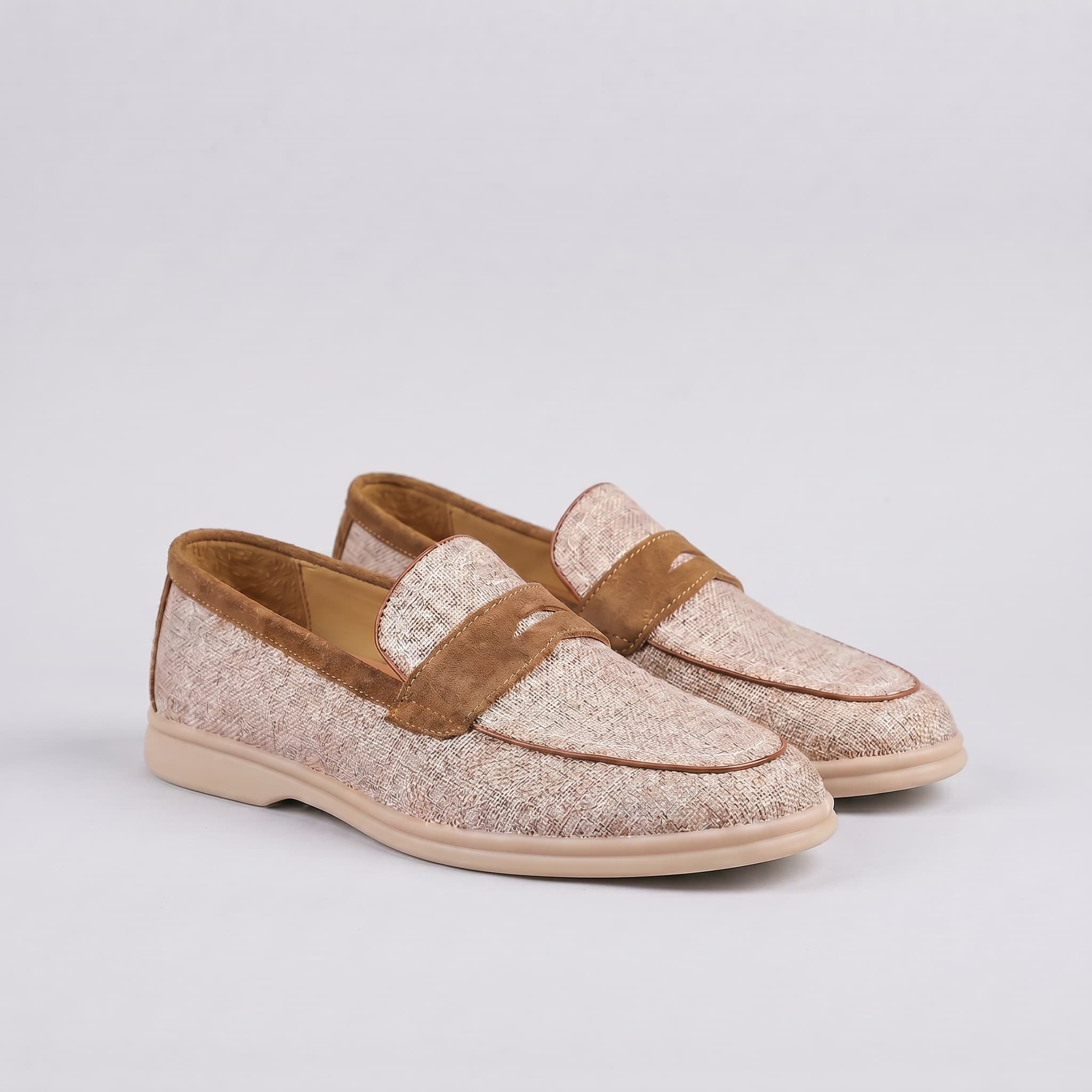 Pair of loafers with brown and beige color scheme on a light gray background