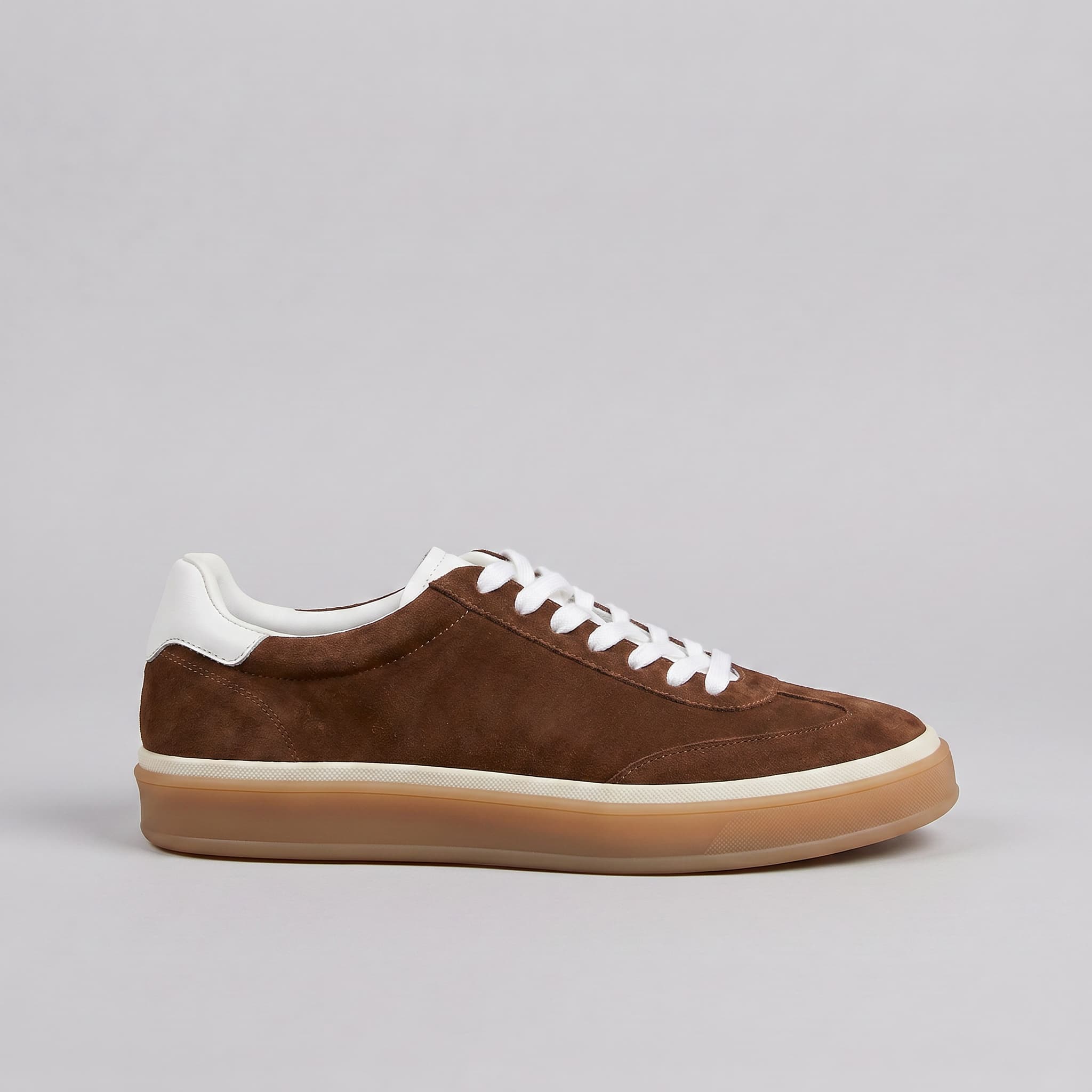 Brown suede sneaker with white laces on a gray background